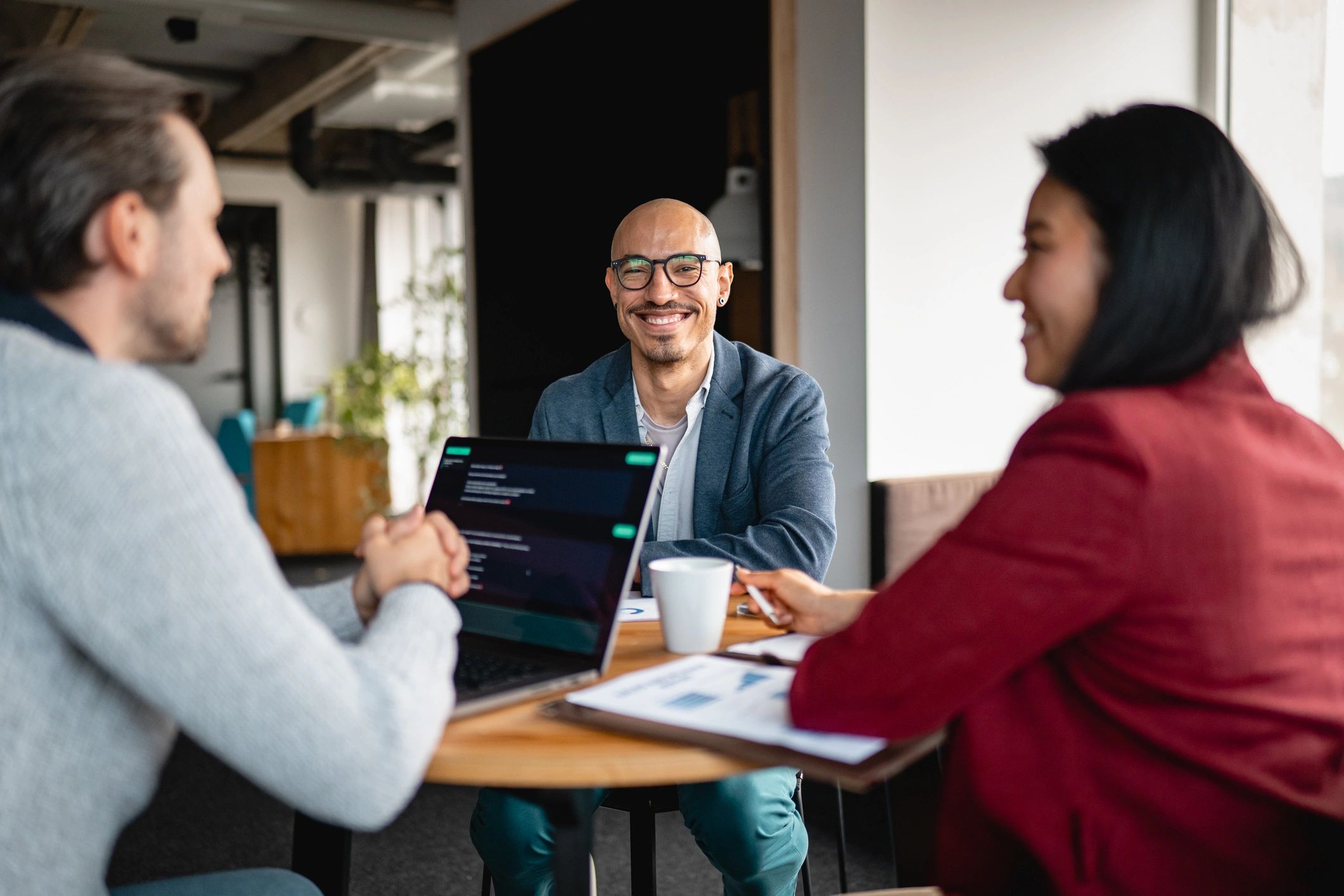Business team collaborating around an AI-enabled laptop